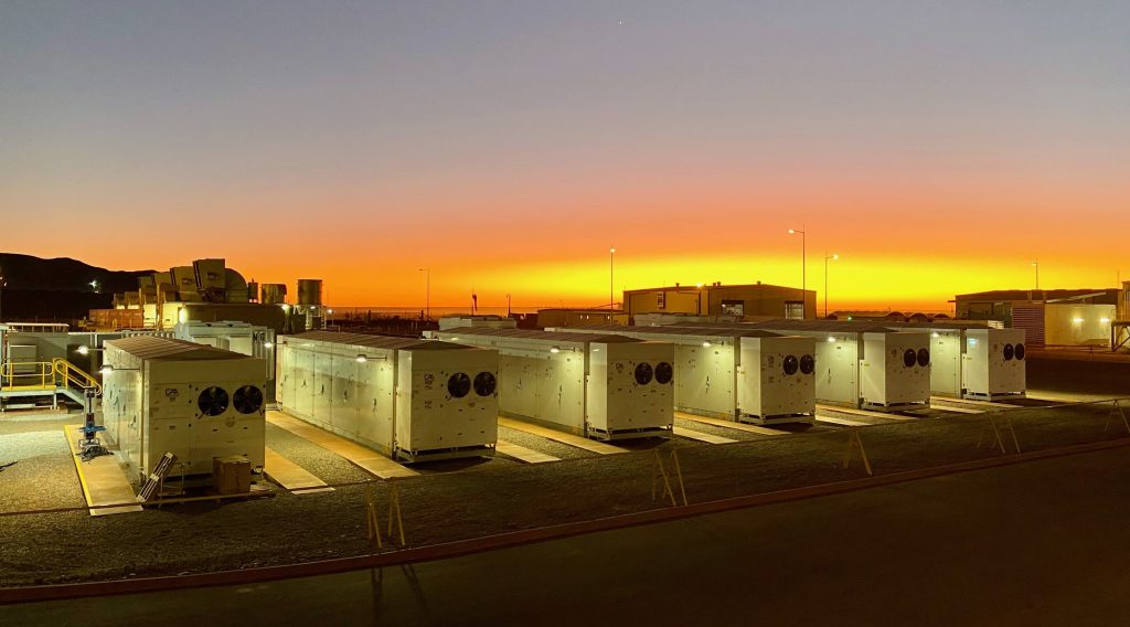 Rows of large‑scale battery energy storage system units installed at a power station at sunset, supporting grid stability and solar energy integration.